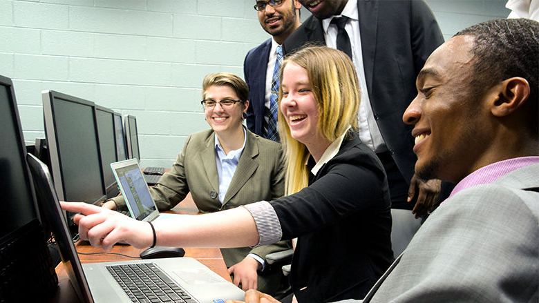 Several students looking and pointing at computer screen