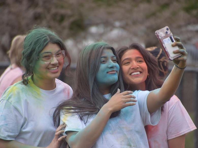 Three students smiling at phone for photo